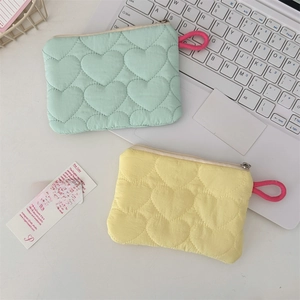 Close-up of quilted heart pattern storage pouches in mint and yellow on laptop