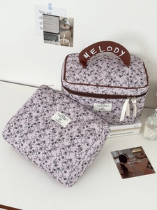 Dettaglio di trousse in velluto a coste floreale con motivo trapuntato e manico in pelle