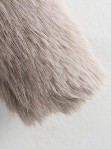 Dettaglio macro della morbida pelliccia ecologica rosa chiaro su un cappotto da donna