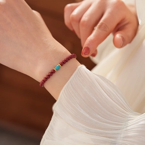 Detailed macro view of cinnabar red beads with turquoise barrel and gold spacers on wrist