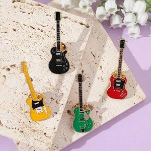 Detail of four colorful electric guitar enamel pins on a textured stone display stand