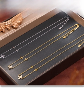 Detail of PVD electroplated gold and silver clover necklaces with zircons in a box