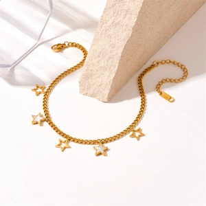 Macro detail of gold stainless steel anklet showing star charms and S.STEEL hallmark