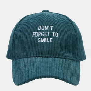 Detailed texture of dark green corduroy baseball cap with Smile slogan embroidery