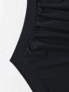 Close-up of black slimming halter swimsuit featuring ruched side pleats and fine stitching