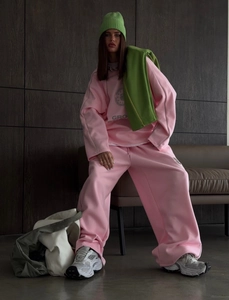 Detail of pink oversized sweatshirt with contrast green accessories and logo print