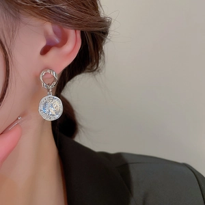 Detail of silver asymmetric chain earrings with pearl and portrait coin pendant on model
