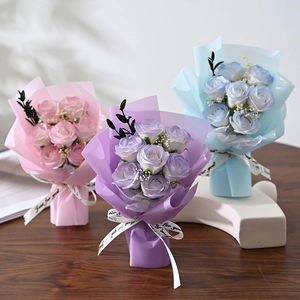 Three handmade soap rose bouquets in pink, purple, and blue on a rustic wooden table