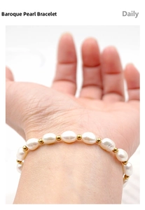 Dettaglio del bracciale con perle barocche e distanziatori dorati sul polso