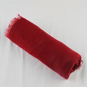 Close-up of red cotton linen scarf with textured crinkle fabric and frayed fringe edges