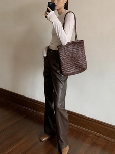 Detail view of dark brown woven tote bag paired with minimalist earth tone styling