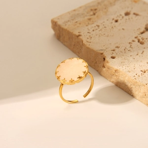 Détail de bague dorée ajustable avec pierre rose ronde et gravures d'étoiles