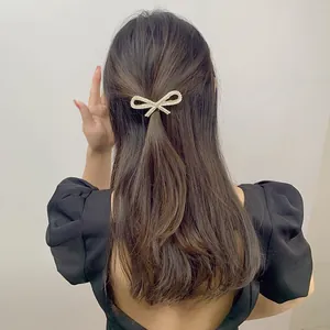 Close-up of a sparkling rhinestone bow hair clip styled on a woman's half-up hairstyle