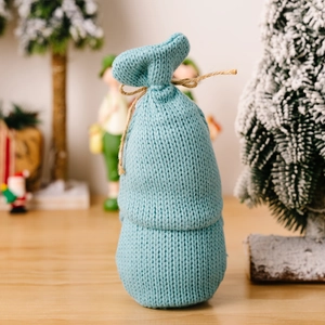 Close-up of a blue knitted Christmas gift bag tied with natural jute twine