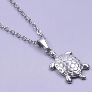 Detail view of a silver turtle pendant with shell texture on a simple O-shaped chain