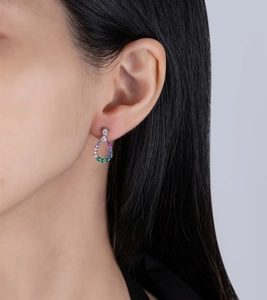 Close-up of teardrop hollow earrings with colorful cubic zirconia on a female model's ear