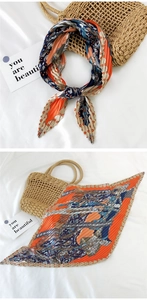 Detail of pleated silk scarf featuring vibrant orange and navy blue geometric patterns