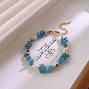 Detail of beaded bracelet with blue stones, pearls and gold lobster clasp closure