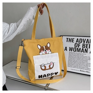Detail showing bright yellow canvas tote bag with cartoon corgi print and happy text