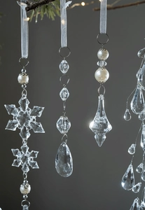 Clear acrylic Christmas ornaments featuring snowflakes, teardrops and pearls on silk ribbons
