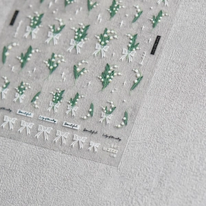 Detail view of 3D embossed nail stickers with lily of the valley and white lace bows