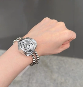 Vue détaillée du bracelet à perles rose argentée avec breloque fleurie en métal