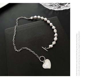 Detail of heart pendant necklace with baroque pearl and gold chain with OT buckle