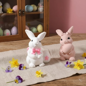 Easter bunny figurines set with pink bow and colorful eggs for festive spring decor