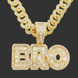 Close-up of gold iced-out BRO pendant necklace featuring sparkling pavé crystals