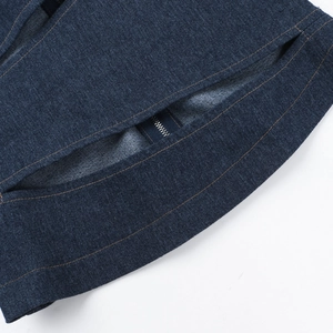 Detailed close-up of dark blue denim vest with metal zipper and reinforced stitching