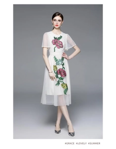 Détail de la robe midi blanche avec broderies florales roses complexes et paillettes