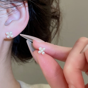 Detailed view of gold plated clover earrings with white pearls and sparkling zirconia