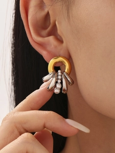 Detail of layered gold hoop earrings with white pearls and silver metal tassels on a model