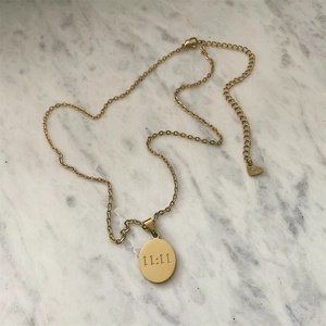 Gold oval 11:11 necklace in stainless steel on white marble background