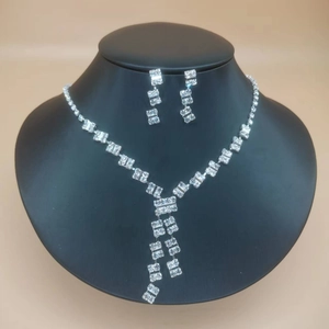 Close-up of sparkling rhinestone necklace and earrings set on a black jewelry stand