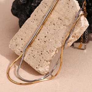 Double-layered 18K gold and silver snake chain necklace on minimalist stone base