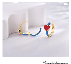 Detailed view of gold hoop earrings with blue enamel and red heart featuring micro inlaid zirconium