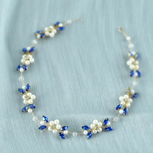 Detailed close-up of bridal headpiece with white pearls and blue crystals on gold wire