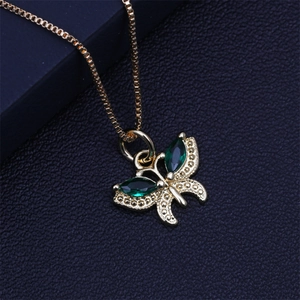 Detail of a golden butterfly pendant with green gemstones on a box chain for women