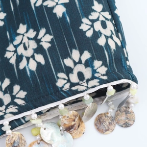 Detailed macro shot of blue floral fabric featuring handmade bead and shell tassels