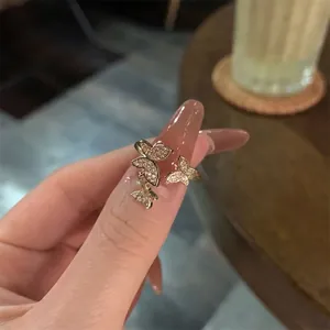 Détail de bague double couche dorée avec des charmes papillons sertis de zircons