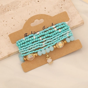 Detail view of multi-layer bohemian beaded bracelets with turquoise and gold crystal charms