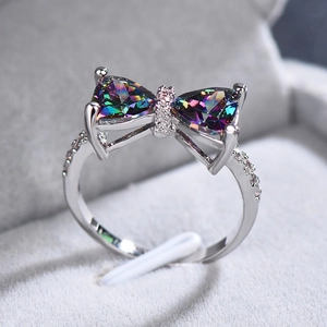Macro shot of silver bow ring featuring iridescent colorful gemstones and zircon stones
