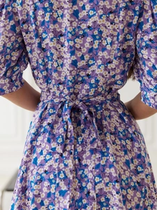 Close-up of waist tie and bow detail on a purple floral short sleeve dress