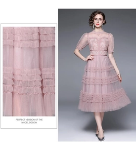 Détails de broderie et texture de tulle multicouche de cette robe rose à volants