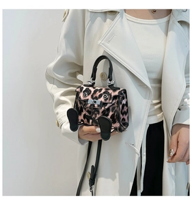 Detail of pink leopard print mini bag with cartoon eyes and silver metal turn lock