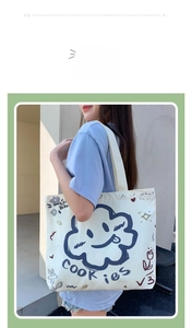Detailed view of canvas tote bag featuring blue cloud graphic and graffiti text prints