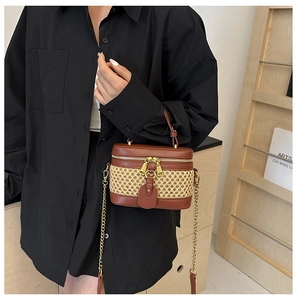 Chic brown PU leather and straw woven bucket bag held by a model in a minimalist setting
