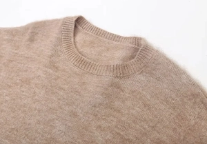 Détail du col rond et de la texture brossée douce sur un pull en tricot marron élégant