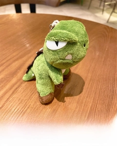Close-up of green plush dinosaur keychain with angry expression and metal buckle